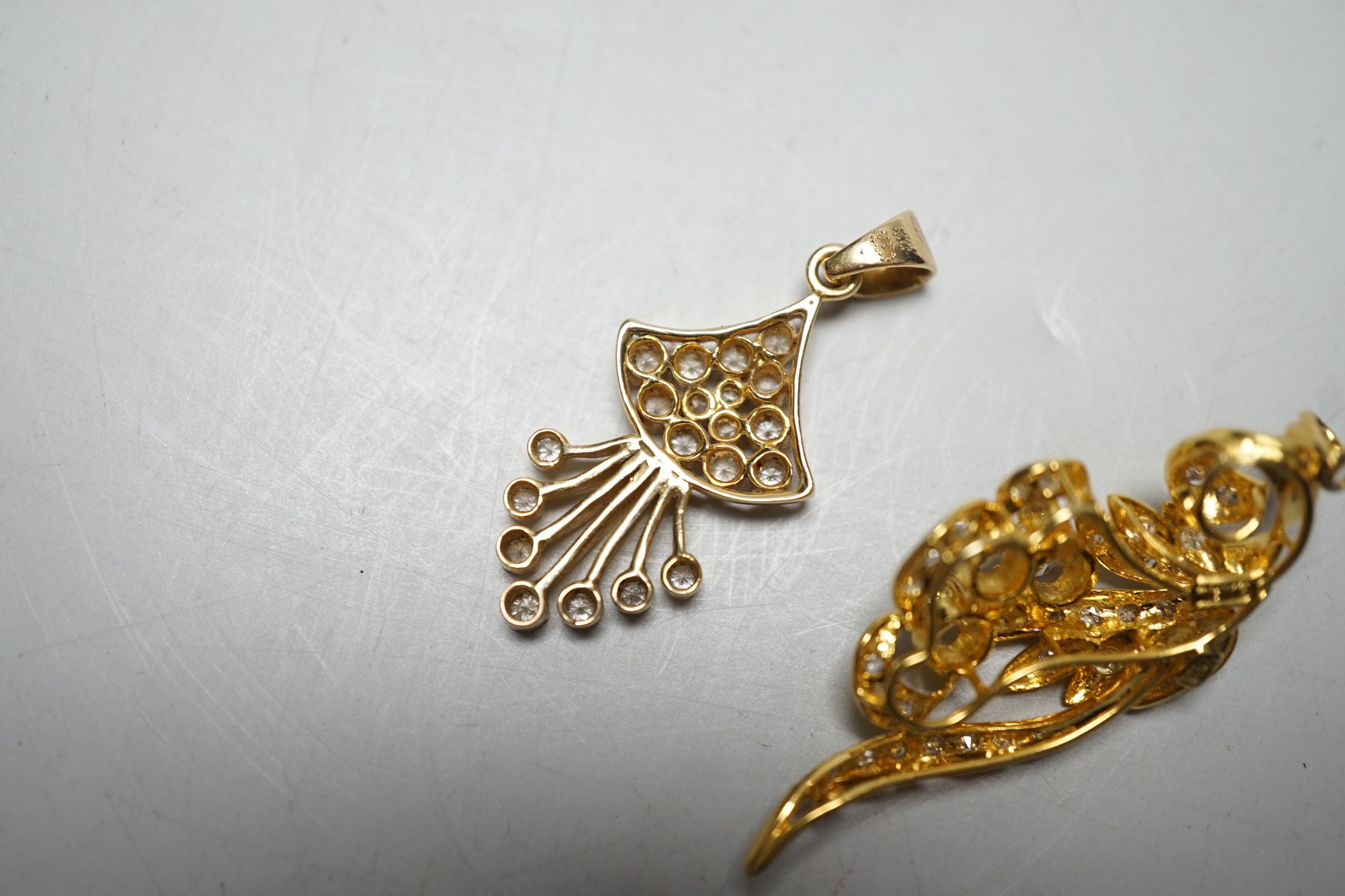 An Earl 18k yellow metal and diamond cluster ser scrolling pendant, overall 46mm and a yellow metal and diamond cluster set fan shaped pendant, gross weight 11.8 grams.